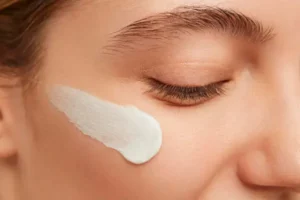 kawałek twarazy kobiety kremem nałożonym na policzku