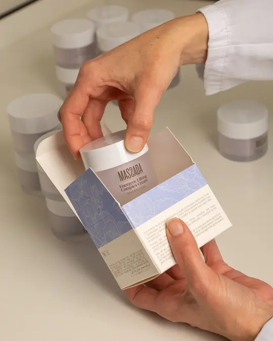 ręce kobiety, która wyciąga z pudełka krem z kwasem hialuronowym